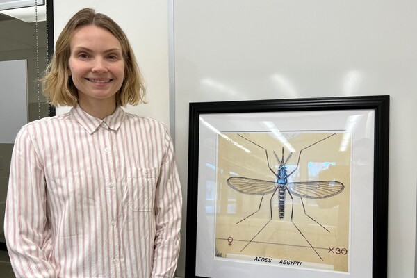 Kathryn next to a framed image of a mosquito