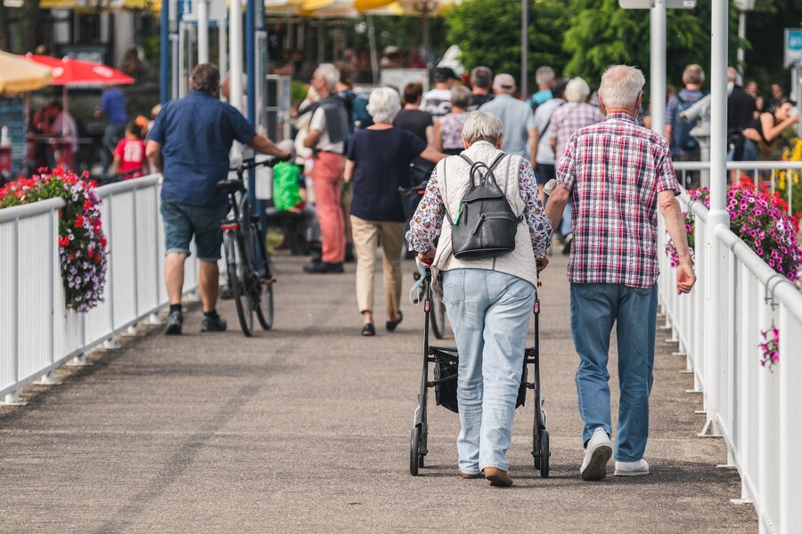 An elderly couple is walking down a sidewalk 